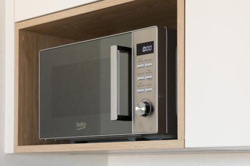 a microwave oven on a shelf in a wall at Sun & Beach Apartments Bel Mare with Parking by Noclegi Renters in Międzyzdroje