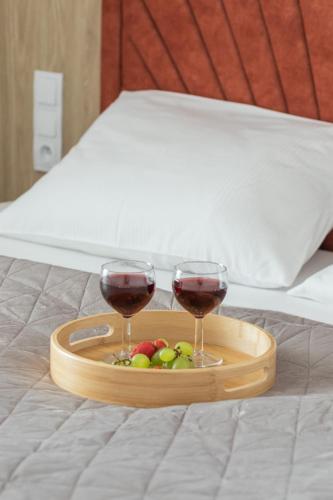 two glasses of wine and fruit on a tray on a bed at Sun & Beach Apartments Bel Mare with Parking by Noclegi Renters in Międzyzdroje