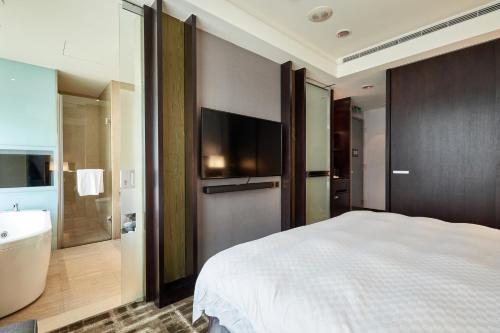 a bedroom with a bed and a bath tub and a television at The Tango Hotel Taipei Nanshi in Taipei