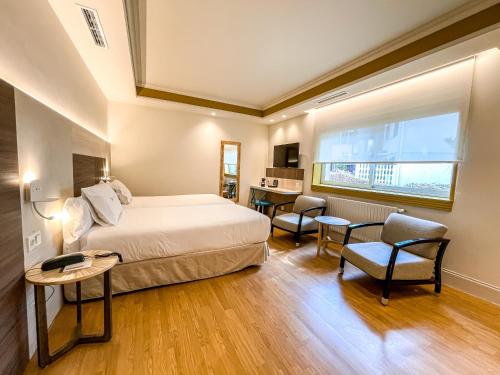a bedroom with a bed and a table and chairs at Hotel Rio Bidasoa in Hondarribia