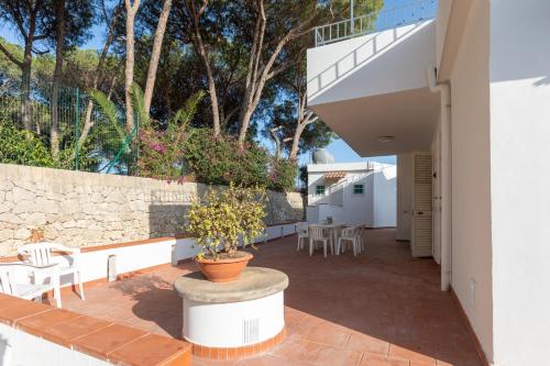a patio with tables and chairs and a stone wall at L'isola di Gianni by Ortigia Apartments in Plemmirio