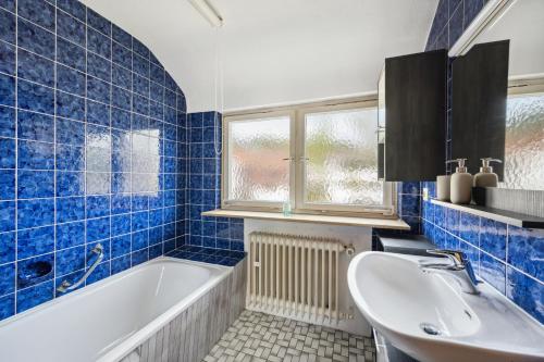 baño de azulejos azules con bañera y lavamanos en home2stay worker Apartment Nürtingen bis zu 200 Betten en Nürtingen