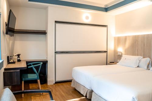 a hotel room with two beds and a desk at Hotel Rio Bidasoa in Hondarribia