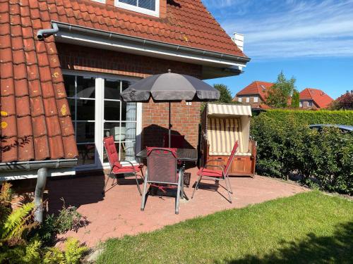 un patio con mesa y sillas bajo una sombrilla en Nr 55 - Ferienwohnung "Leuchtturm" Caspersweg, en Carolinensiel