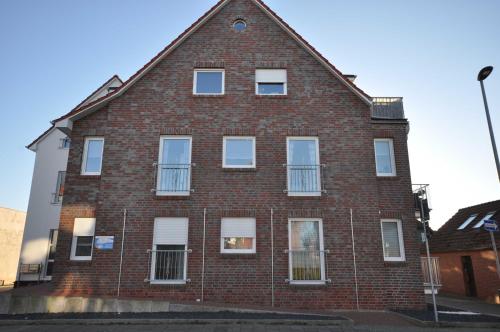 un edificio in mattoni rossi con finestre bianche su una strada di Nr 57 - Ferienwohnung Mühlenstraße a Carolinensiel