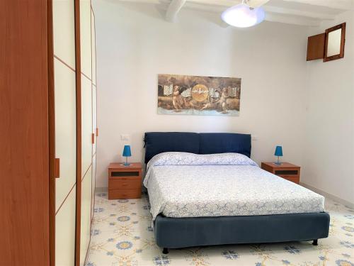 a bedroom with a blue bed and two night stands at Casa Bouganville in Pollara