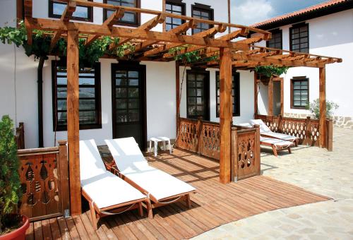 a wooden pergola with white chairs on a patio at Wine & Spa Complex Starosel in Starosel
