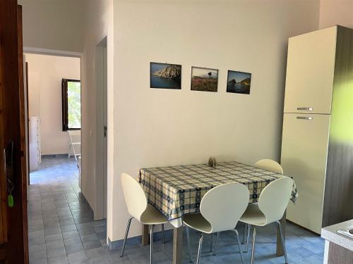 a dining room with a table and white chairs at Casa Bouganville in Pollara