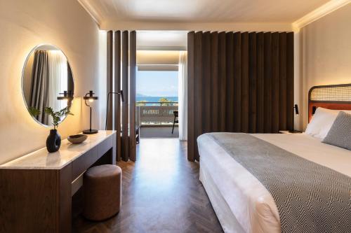 ein Hotelzimmer mit einem großen Bett und einem Spiegel in der Unterkunft Kerkyra Blue Hotel & Spa by Louis Hotels in Korfu-Stadt