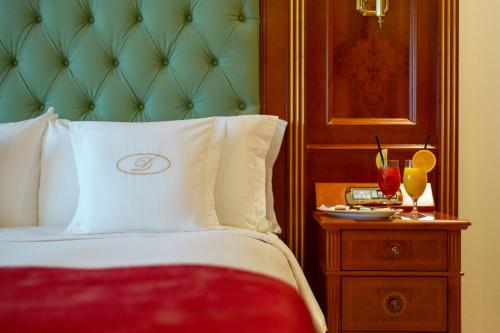 a bedroom with a bed with a green headboard and a table at Swiss Diamond Hotel Prishtina in Pristina