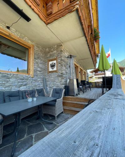 a patio with a table and chairs and a stone wall at Alpenhof in Lermoos