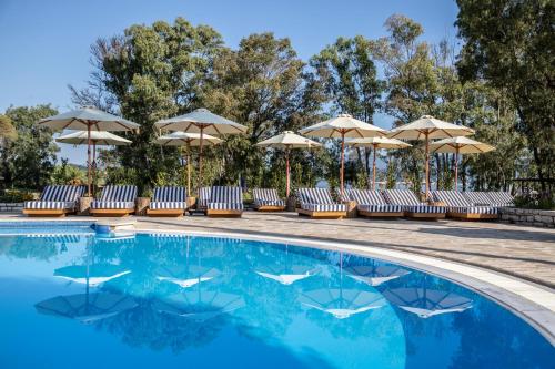 a pool at a resort with chairs and umbrellas at Kerkyra Blue Hotel & Spa by Louis Hotels in Corfu Town