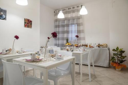 un comedor blanco con mesas blancas y sillas blancas en Due Passi, en Palermo