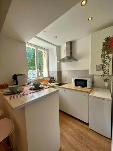 une cuisine avec des armoires blanches et un comptoir dans l'établissement Le petit Marnais - 15mn Disneyland - 25mn Paris, à Pomponne