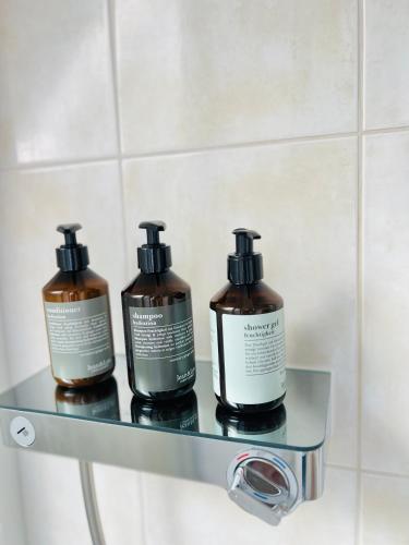 three bottles of soap on a glass shelf in a bathroom at Boutique Appartement in Torgau