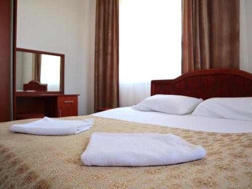two white towels sitting on top of two beds at Jansyn Hotel Restaurant in Karakol
