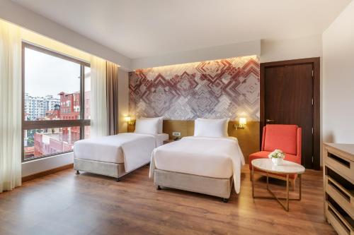 Dusit Princess Kathmandu في كاتماندو: غرفة فندقية بسريرين وكرسي احمر