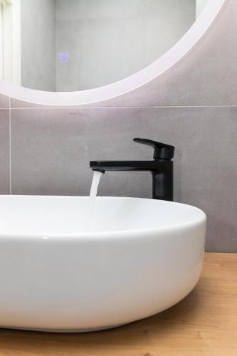 a white sink with a black faucet in a bathroom at Deluxe apartment BRAČOLET private pool in Supetar