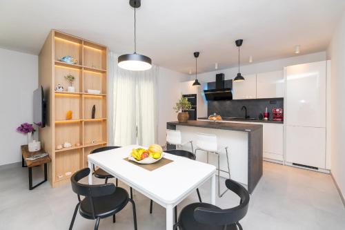 Il comprend une cuisine et une salle à manger avec une table et des chaises blanches. dans l'établissement Deluxe apartment BRAČOLET private pool, à Supetar