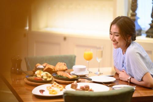 a woman sitting at a table with food and drinks at Sheraton Grande Sukhumvit, a Luxury Collection Hotel, Bangkok in Bangkok