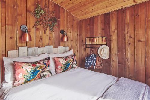 1 dormitorio con paredes de madera y 1 cama con almohadas en Big Sky Hideaway en Leominster