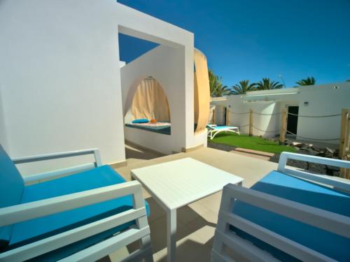 a patio with two chairs and a white table and chairs at Hotel Taimar in Costa Calma