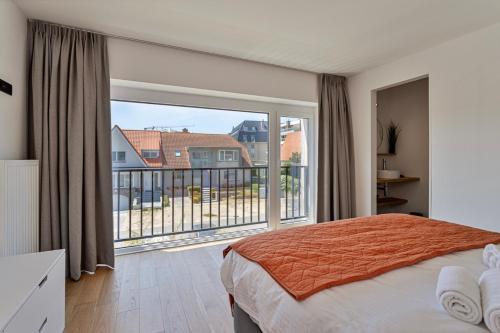 um quarto com uma cama e uma grande janela em Strandparel luxueus duplex appartement met 2 terrassen én parking em Koksijde