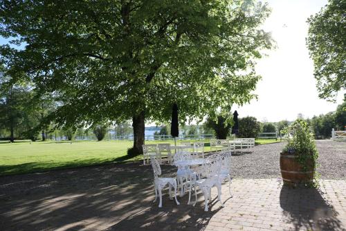 una fila de mesas y sillas blancas bajo un árbol en Åsundsholm Golf & Country Club en Vegby