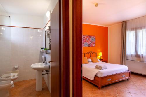 uma casa de banho com uma cama, um WC e um lavatório. em iH Hotels Le Zagare Resort em Villasimius