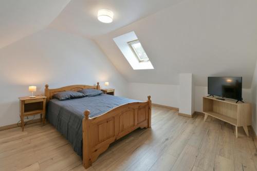 um quarto com uma cama de madeira e uma televisão em Au 2 ailes - Charmante maison pour 7 em Picauville