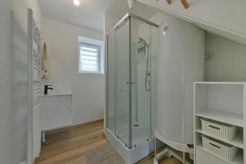 uma cabina de duche em vidro numa casa de banho com paredes brancas em Au 2 ailes - Charmante maison pour 7 em Picauville