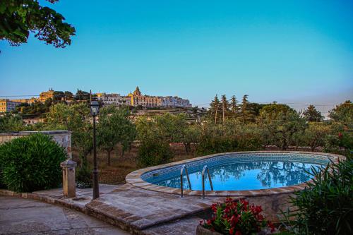 een zwembad in een tuin met een stad op de achtergrond bij Masseria Trulli Bruni in Locorotondo