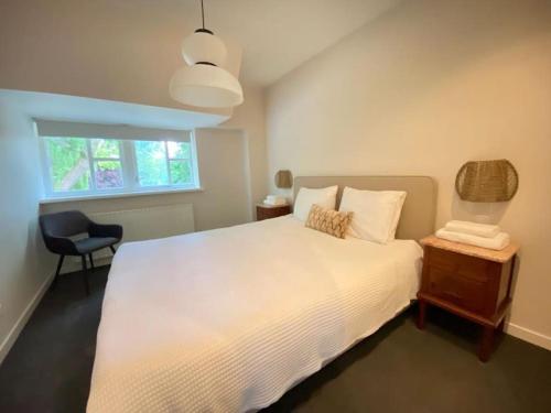 Un dormitorio con una gran cama blanca y una silla. en Parkzicht, en Leeuwarden