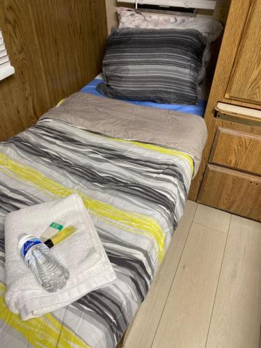 a bed with a towel and a bottle of water on it at House Rooms & RV Rooms Near LAX in Los Angeles
