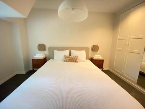 1 dormitorio con 1 cama blanca grande y 2 mesitas de noche en Parkzicht, en Leeuwarden