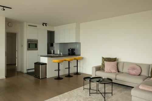 a living room with a couch and a kitchen at UNIEK appartement - mooiste en hoogste uitzicht op Antwerpen! - incl gratis parking in Antwerp
