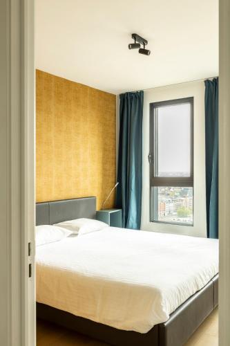 a bedroom with a large bed and a window at UNIEK appartement - mooiste en hoogste uitzicht op Antwerpen! - incl gratis parking in Antwerp