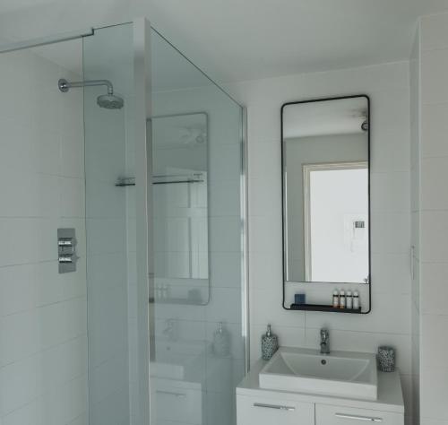 a white bathroom with a sink and a mirror at Stylish Central London Flat with Pool and Terrace in London