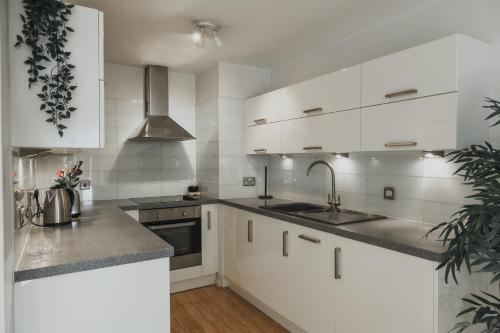 a kitchen with white cabinets and a sink at Stylish Central London Flat with Pool and Terrace in London