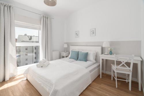 a white bedroom with a white bed and a desk at White Elegance Apartment with AC & FREE GARAGE by Renters in Poznań