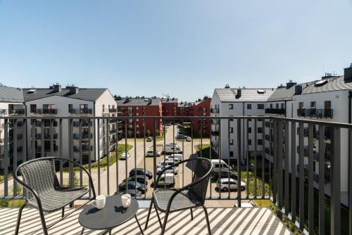 a balcony with chairs and a street with buildings at White Elegance Apartment with AC & FREE GARAGE by Renters in Poznań