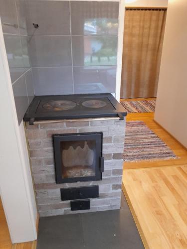 a brick fireplace with a stove in a room at Varakoti Helmeri in Hirvikoski