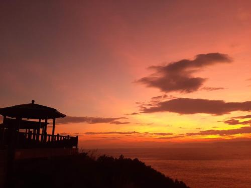 a sunset over the ocean with a gazebo at 大新民宿Da Xin Homestay in Beigan