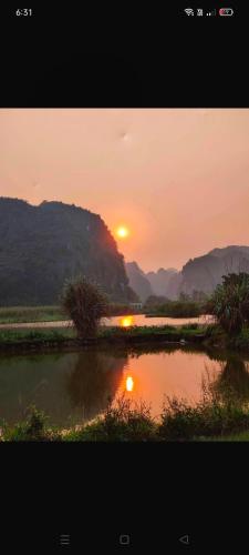 a sunset over a body of water with mountains in the background at Hang Mua Eco Garden in Xuân Sơn