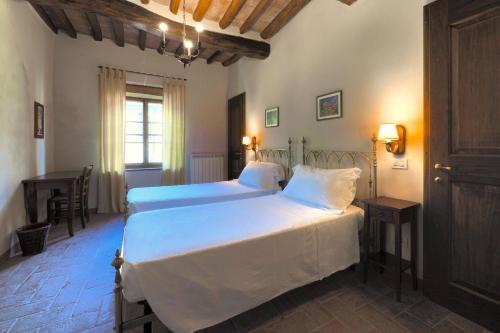 a bedroom with two beds and a desk in it at Castello di Montalto in Castelnuovo Berardenga