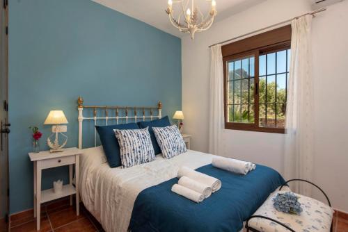 ein blaues Schlafzimmer mit einem Bett und einem Fenster in der Unterkunft El Huertecillo by Vintage Travel in El Gastor