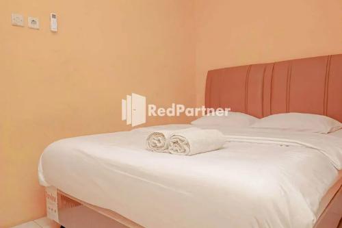 Una cama blanca con dos toallas plegables. en Pondok Damai Guest House Syariah Mitra RedDoorz, en Cirebon