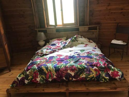 una cama con un edredón colorido en una habitación en Maison ronde atypique en bois, en Carmaux