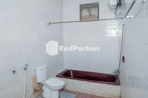 a bathroom with a toilet and a bath tub at Pondok Damai Guest House Syariah Mitra RedDoorz in Cirebon