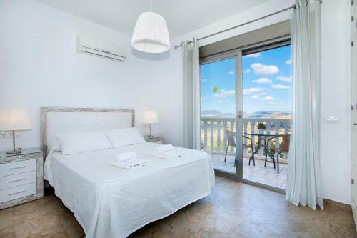 a white bedroom with a bed and a balcony at El Tajaral in El Gastor